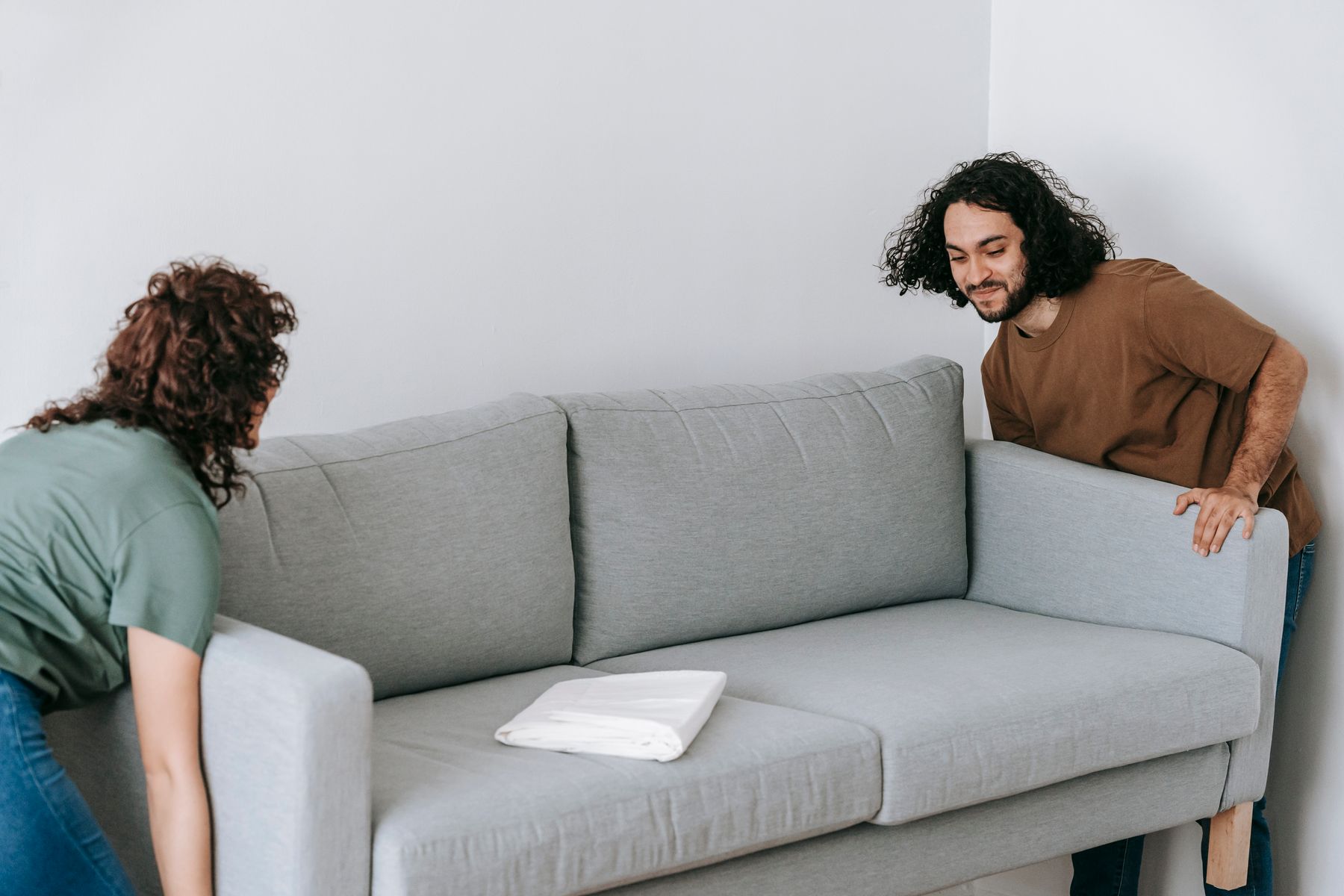 Two people moving a sofa in a bright room